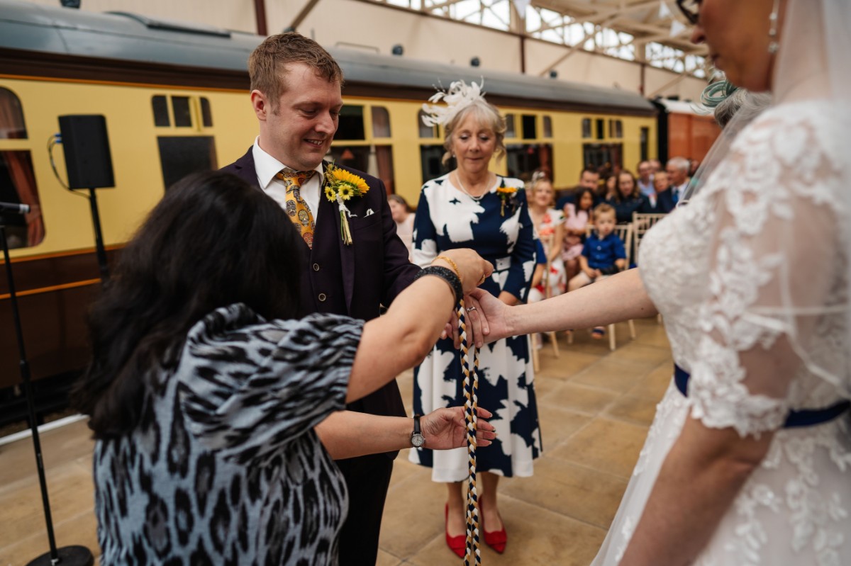 Liz and Paul taking part in a handfasting ritual during their wedding ceremony.