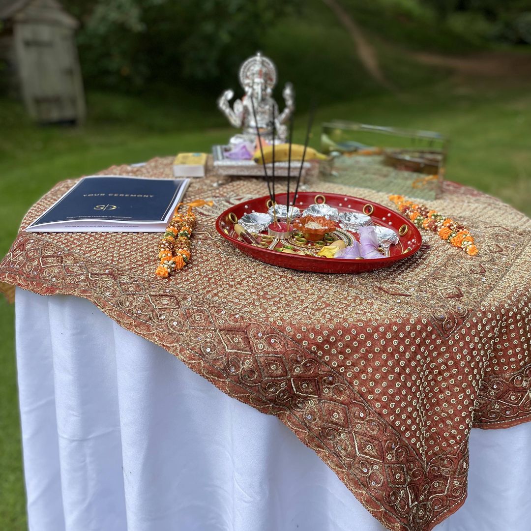 Traditional Indian wedding ceremony table with Ganesh statue, puja thali and flowers