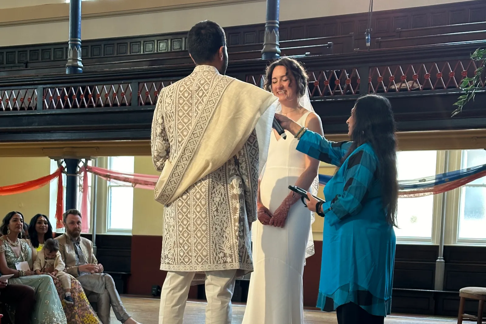 Sonal holds microphone out to couple during ceremony at Round Chapel